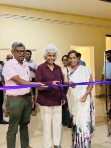 One man and two women cutting a purple ribbon.